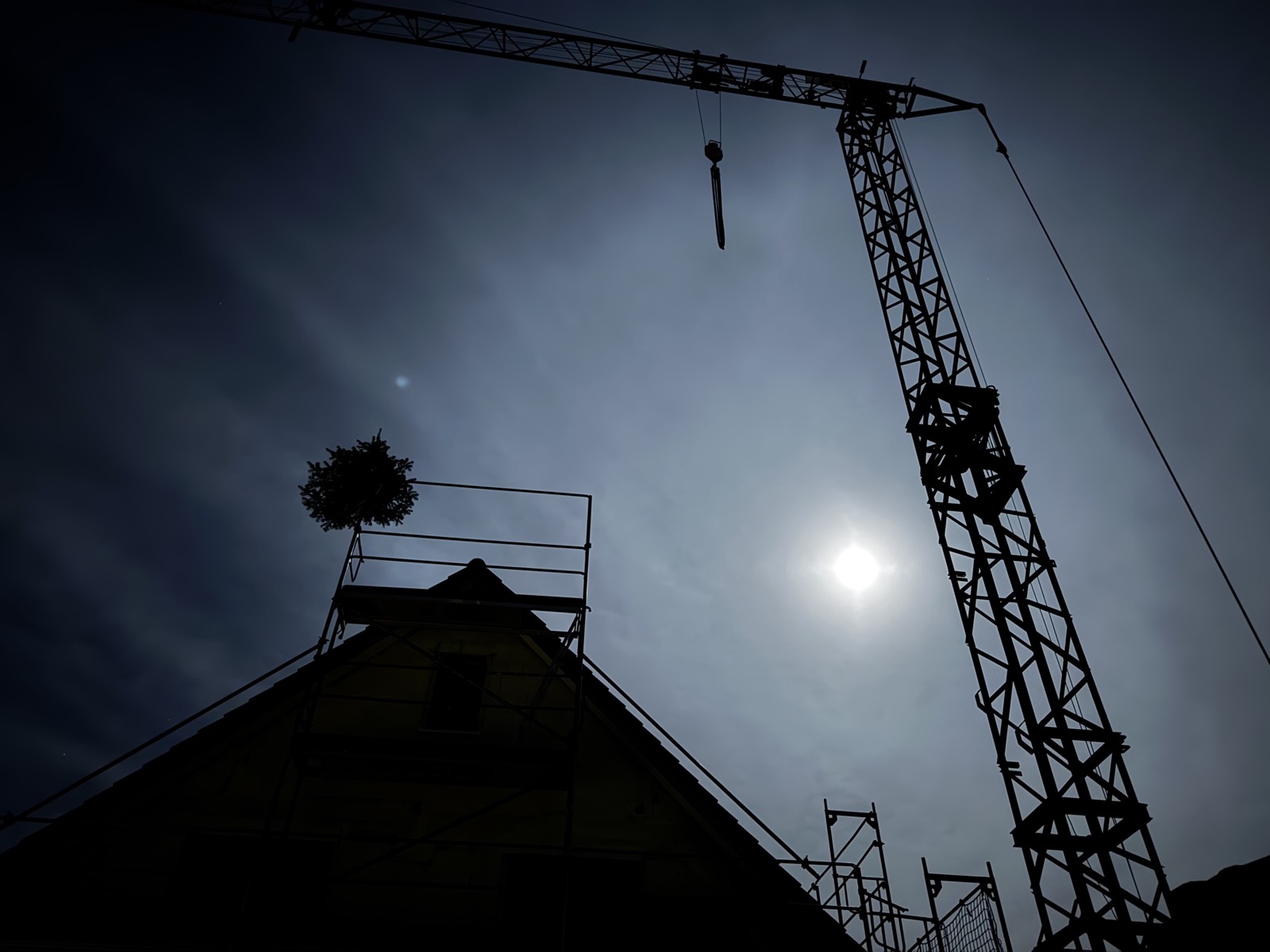 Die Richtkrone über dem Giebel — Abendstimmung an der Baustelle.